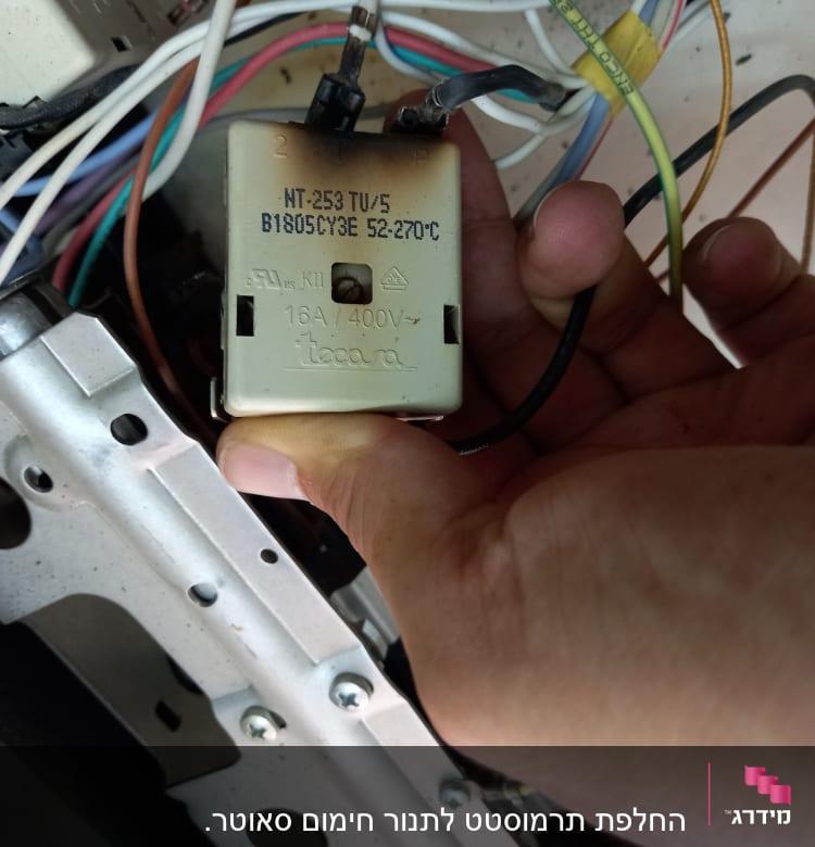 יד מחזיקה רכיב חשמלי עם חוטים צבעוניים